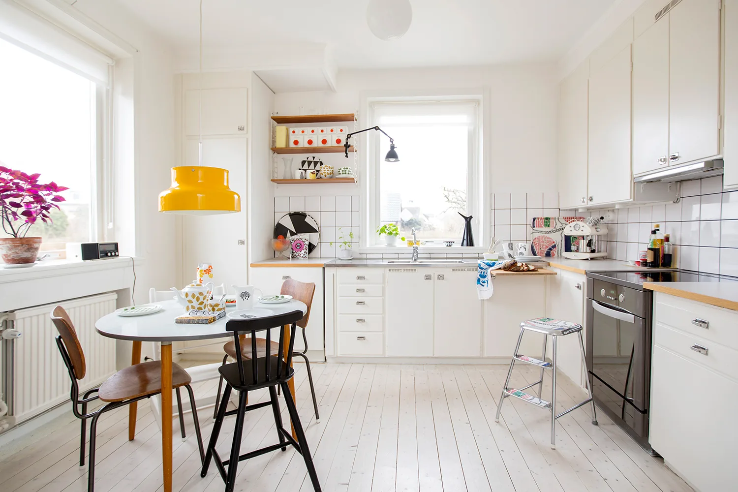 white kitchen with tiled floor, dining table and yellow pendant light
