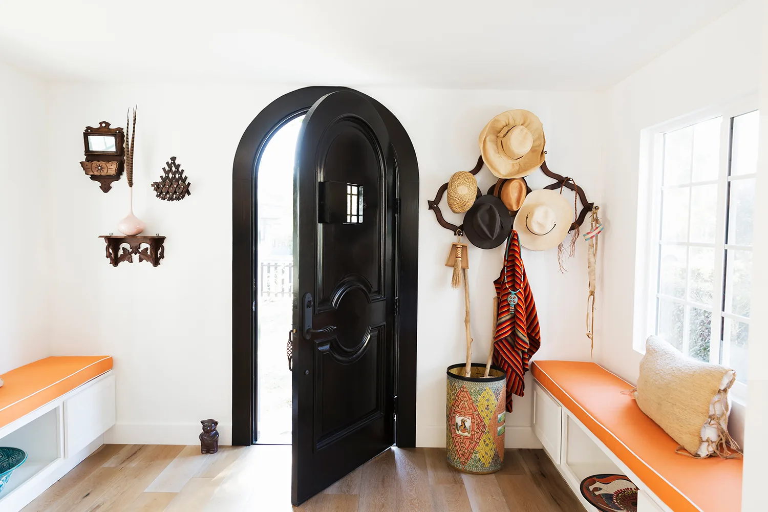 white entry with black door an hats on wall hooks