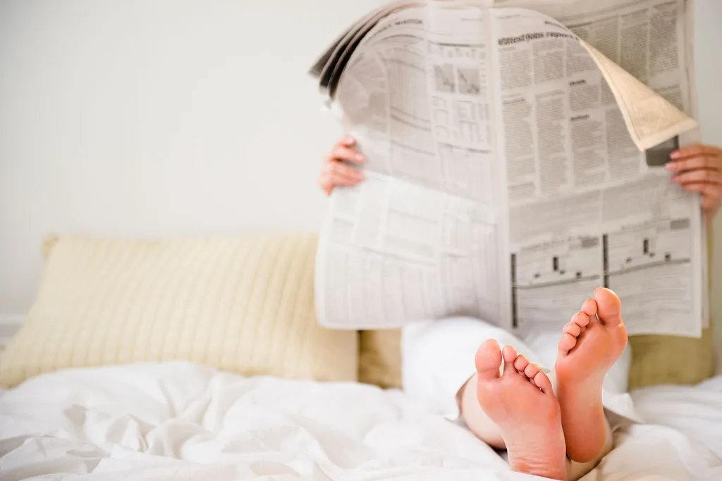 Woman reading newspaper in bed