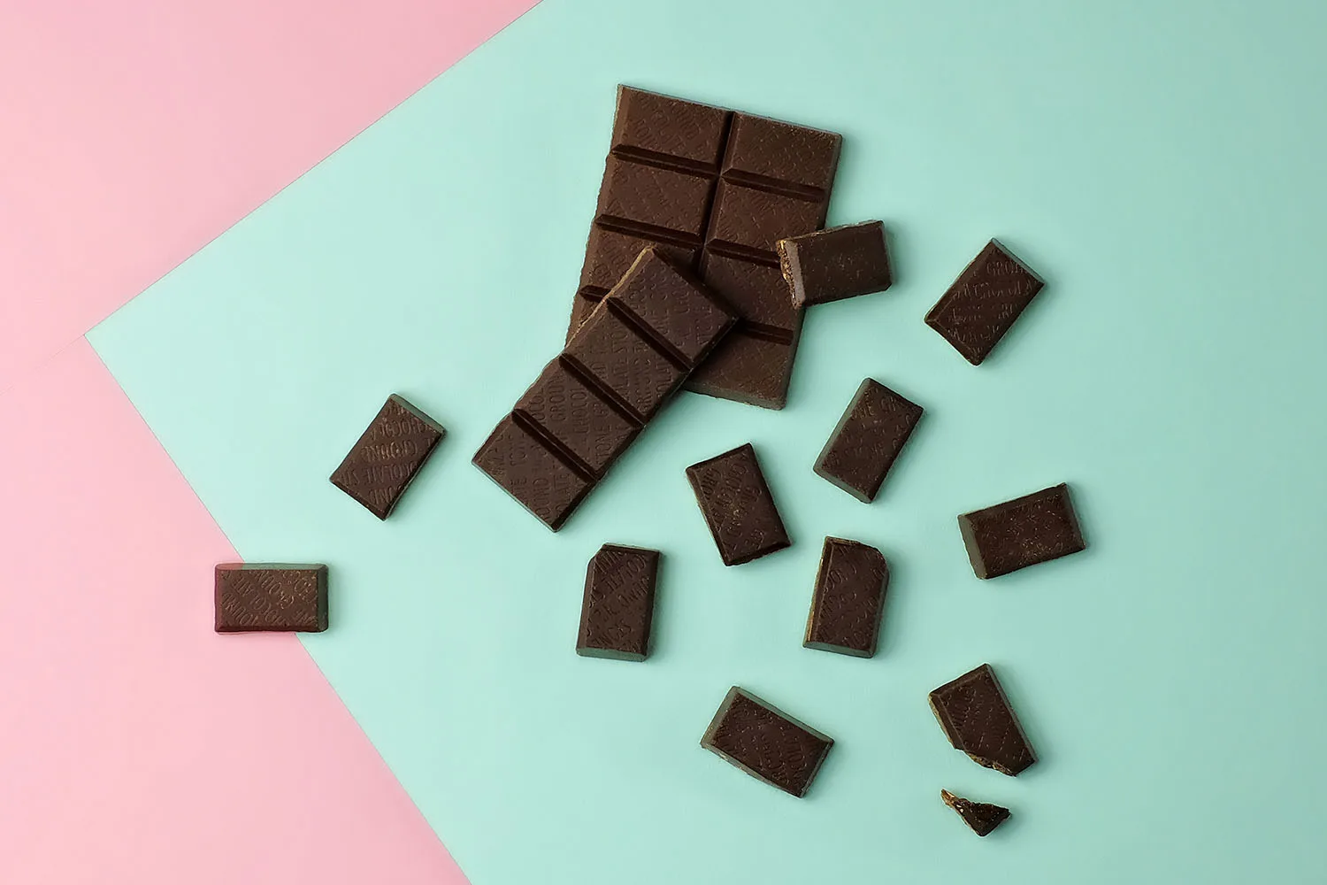 dark chocolate squares on pink and green background