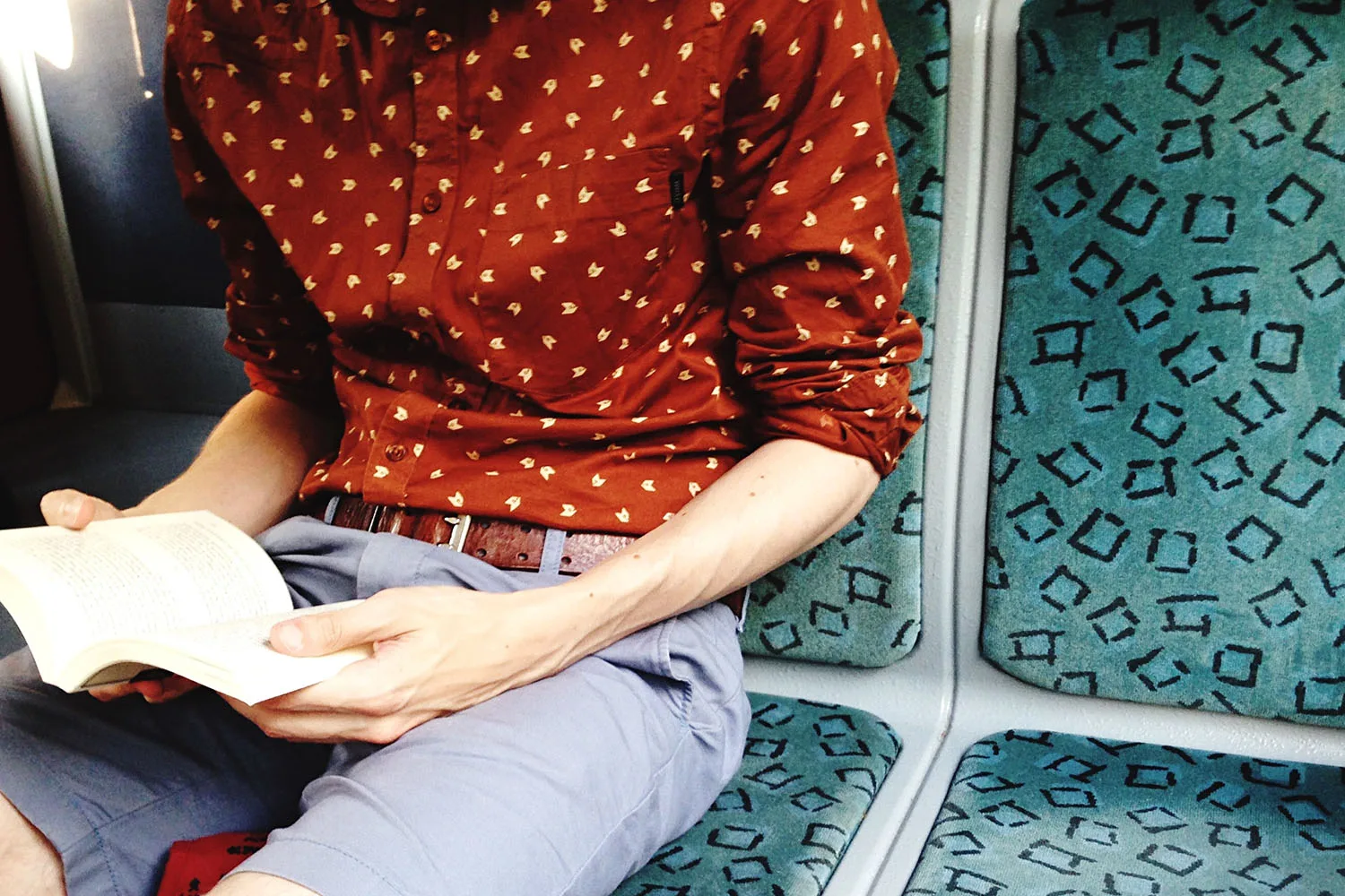 person reading book on train commute