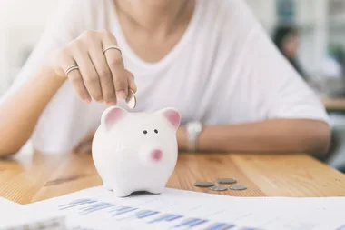woman putting coin into piggy bank