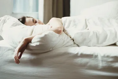 woman asleep in bed with white sheets