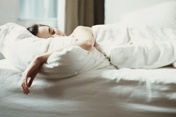 woman asleep in bed with white sheets