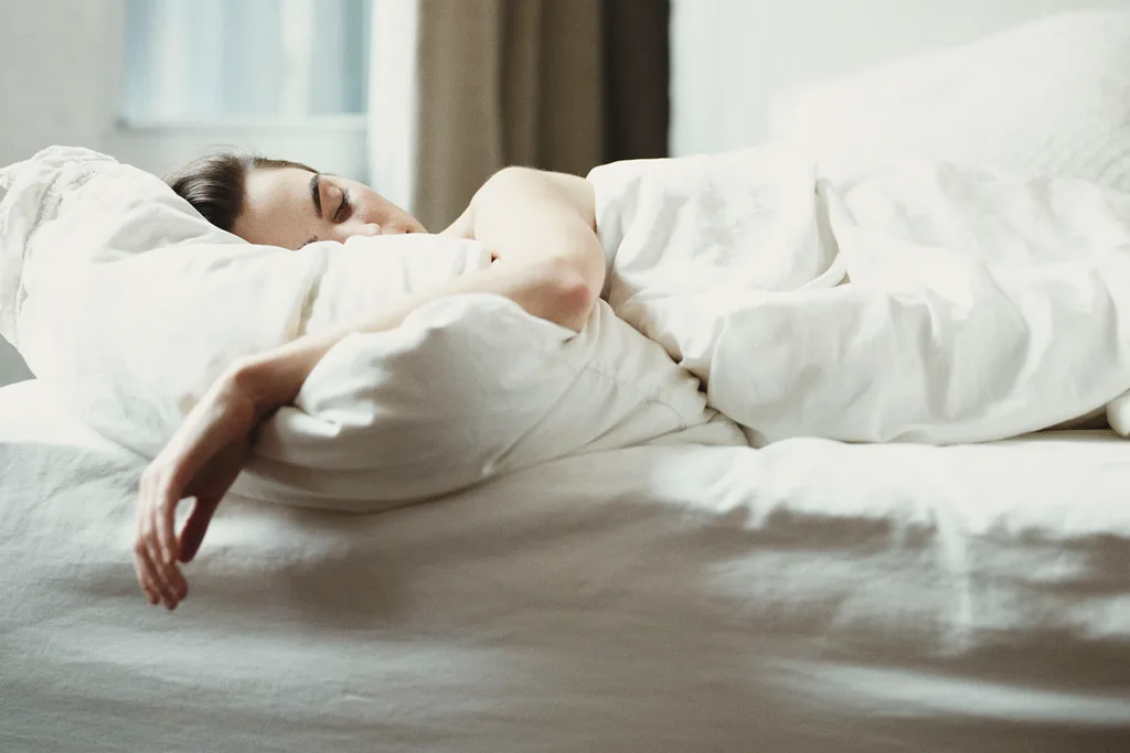 woman asleep in bed with white sheets