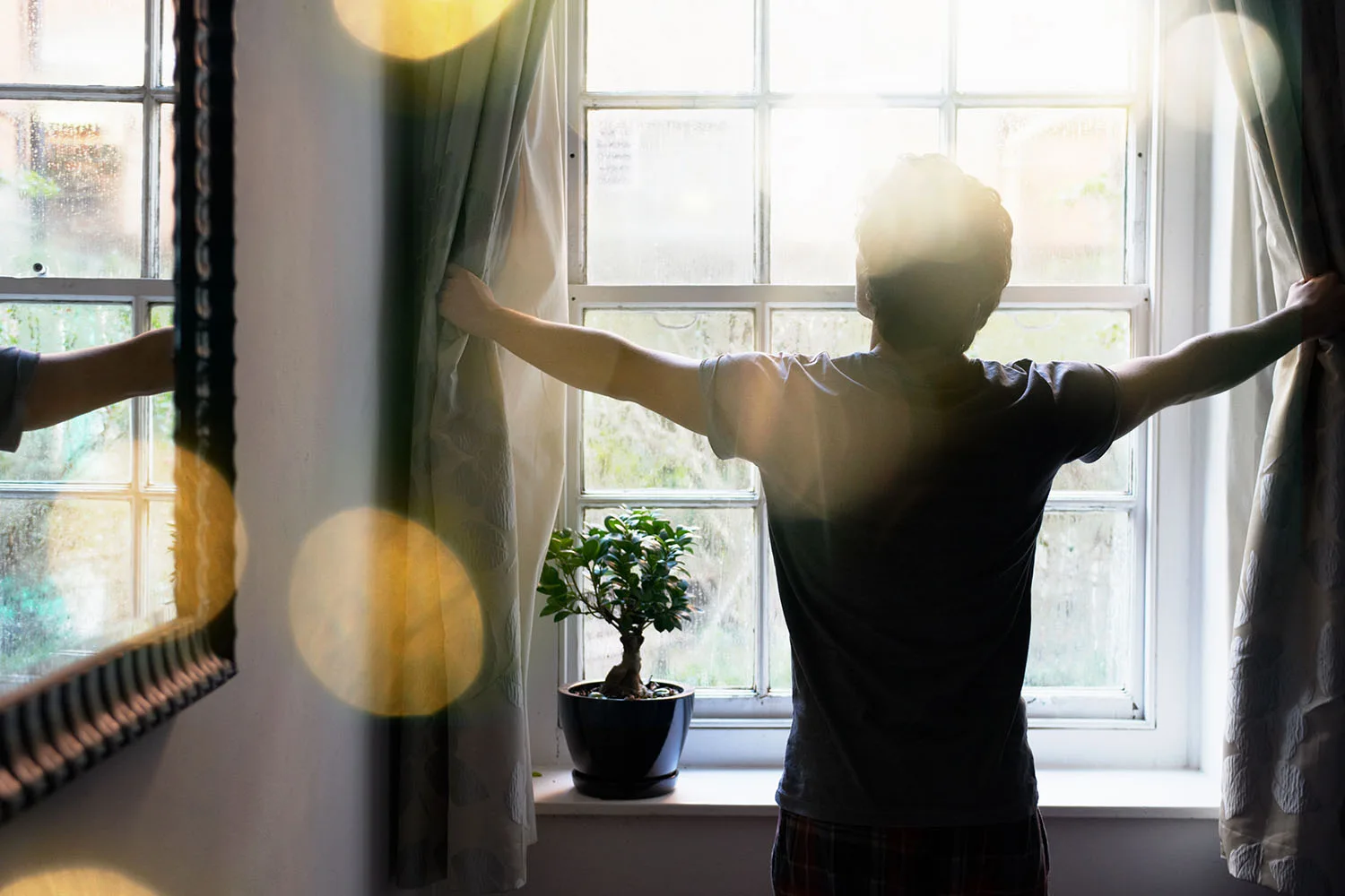 man opening curtains