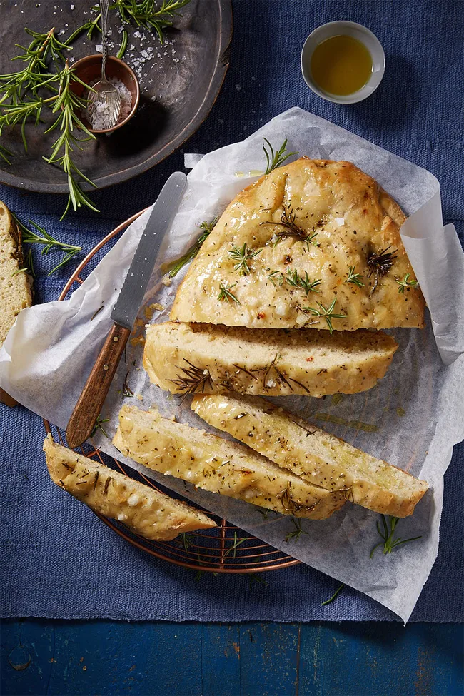 Slow-cooked herb bread on oven baking tray sliced into several pieces