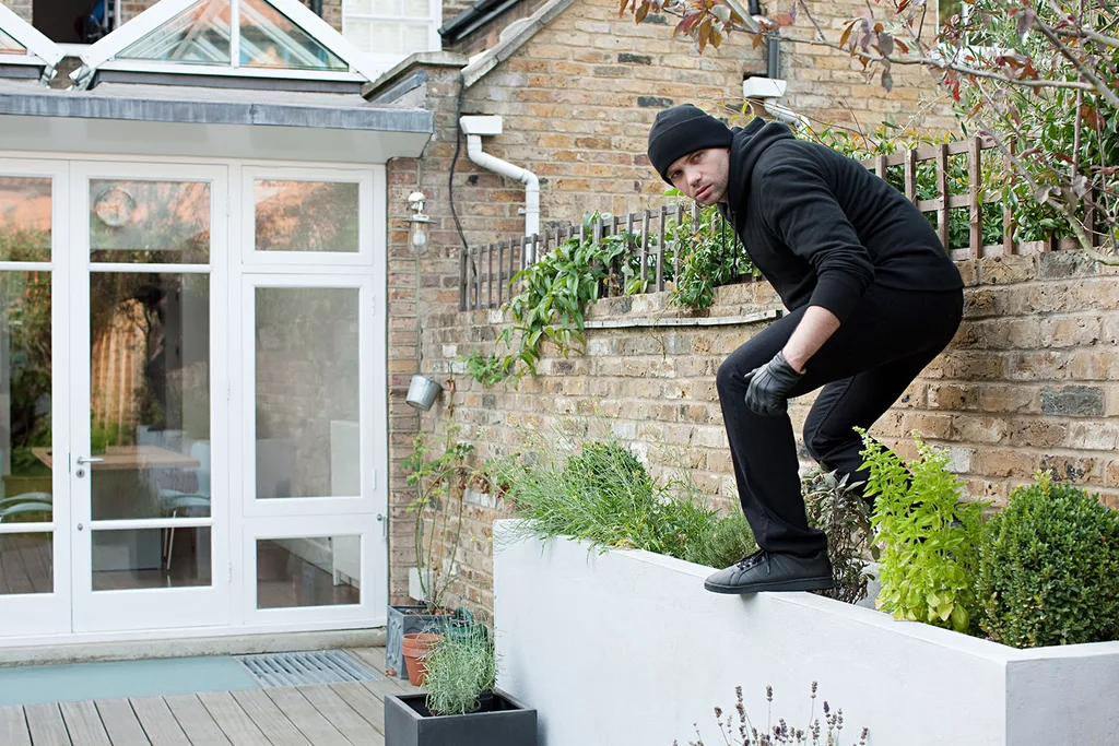 thief climbing over fence