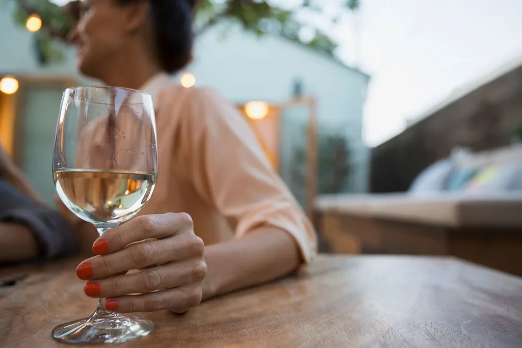 woman holding glass of white wine