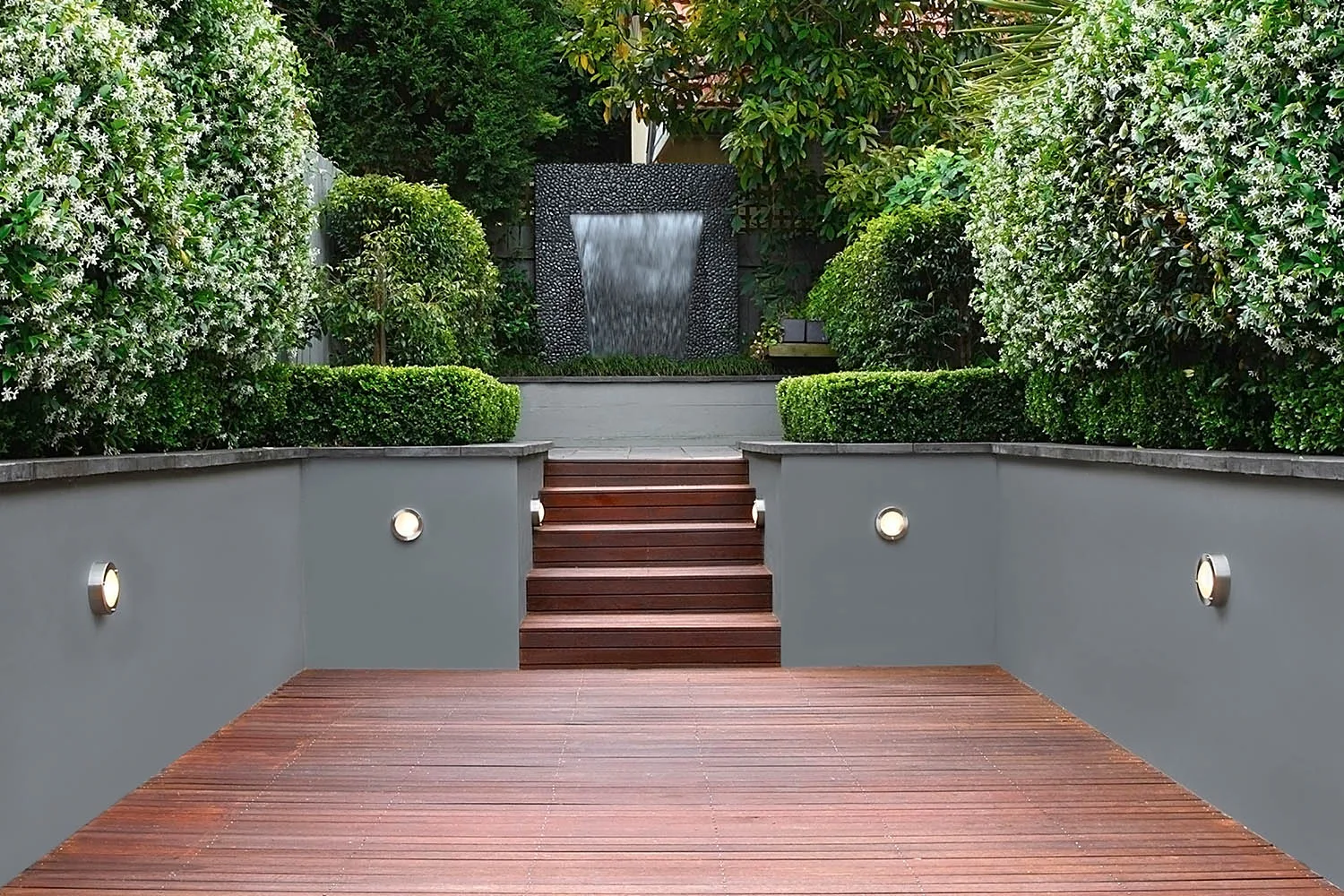 garden backyard deck design idea with grey rendered retaining wall and shrubbery