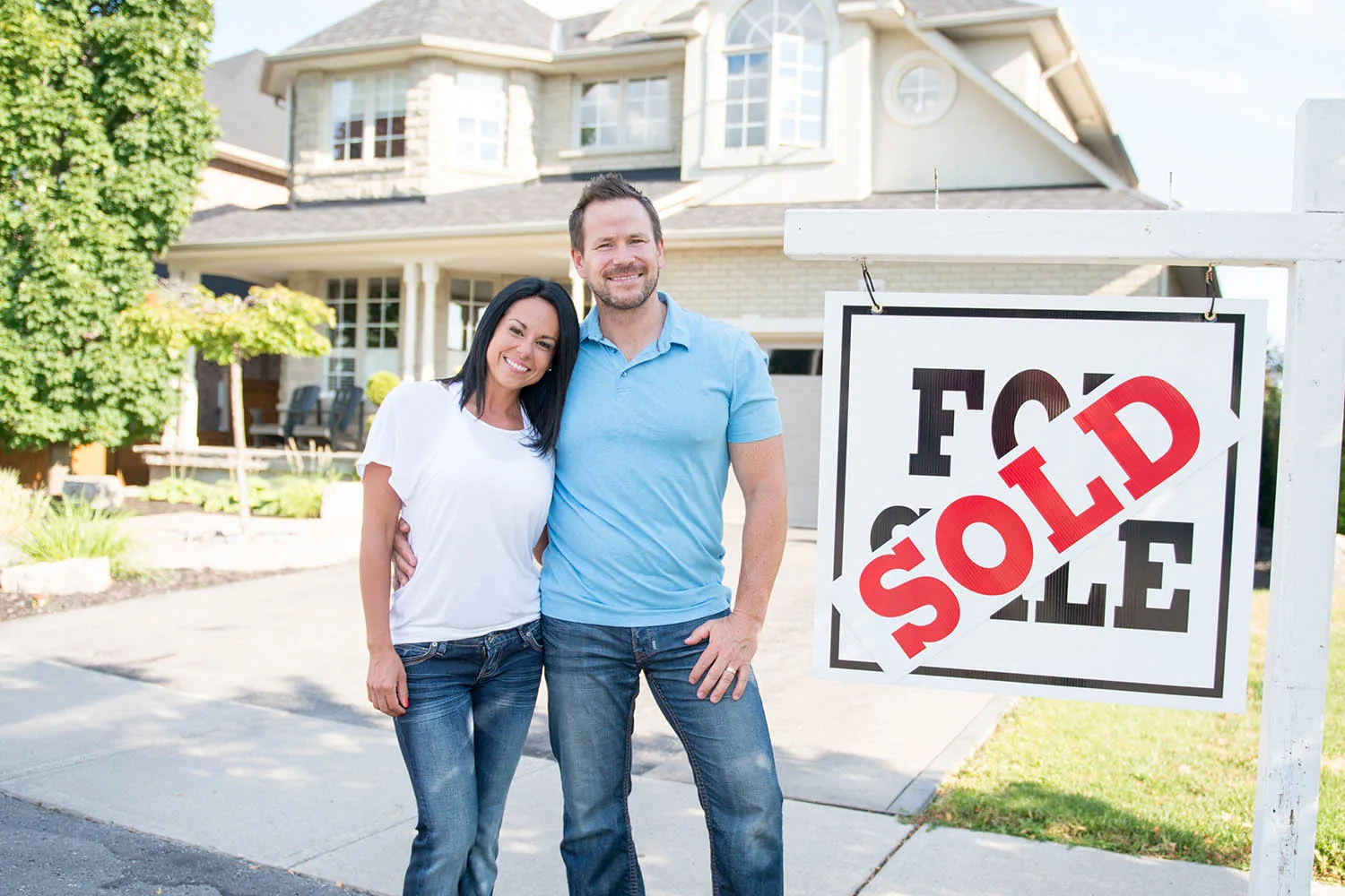 couple standing in front of sold sign
