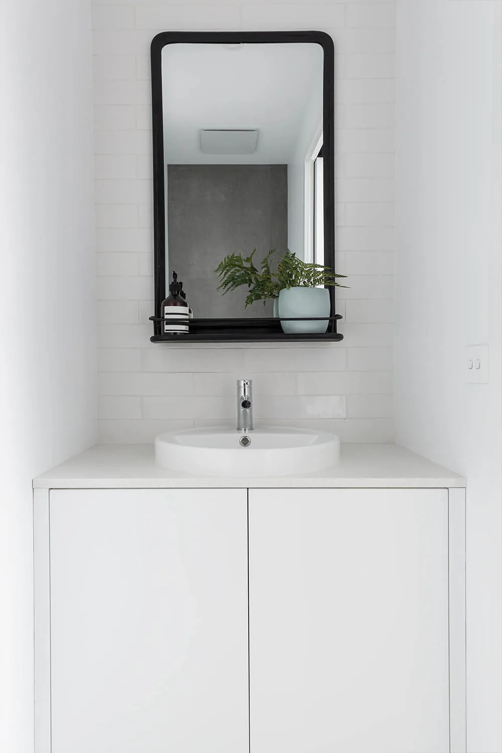 small powder room in white with black mirror