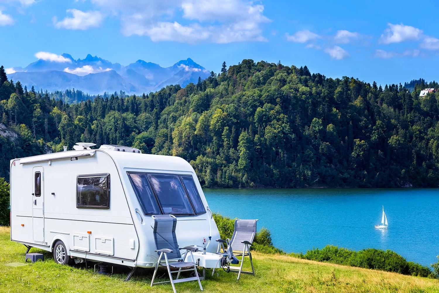 caravan parked on grassy knoll near lake