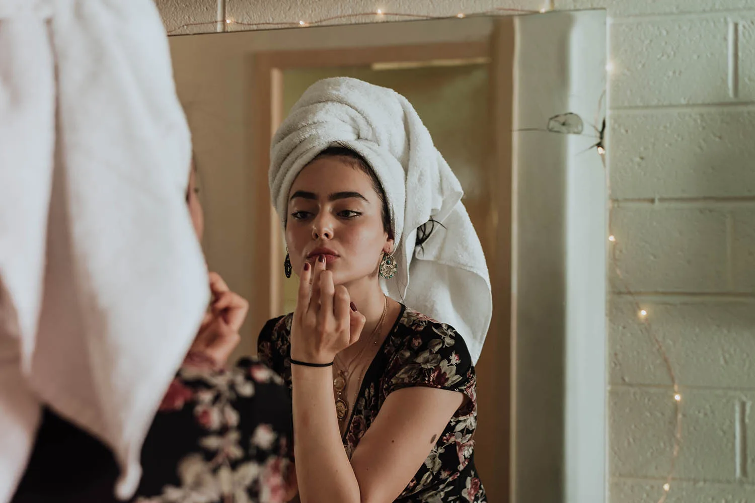 woman putting lip balm on in mirror