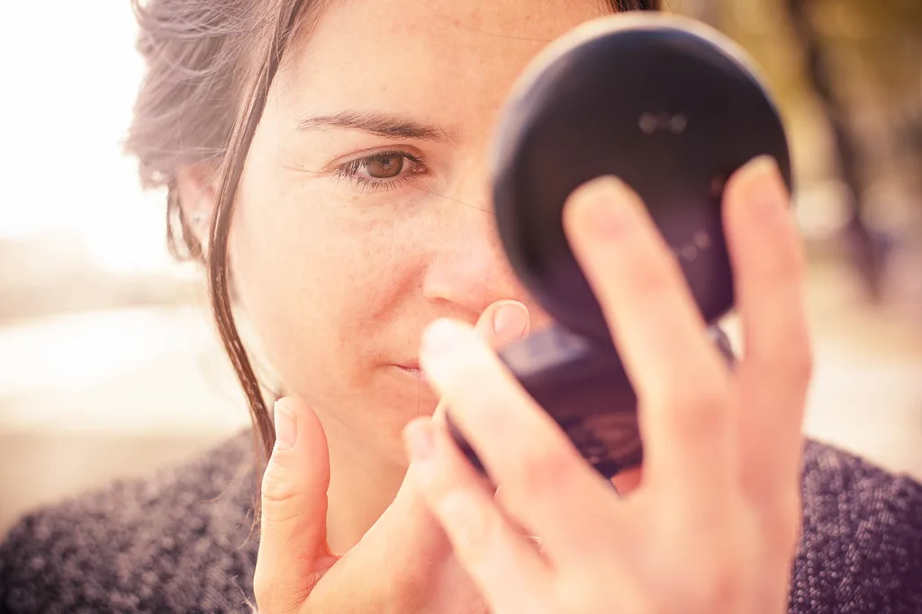 woman looking into compact mirror