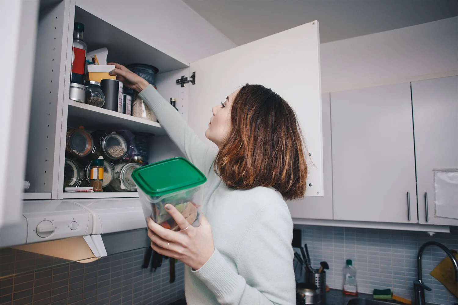 Woman reaching up to pantry shelf