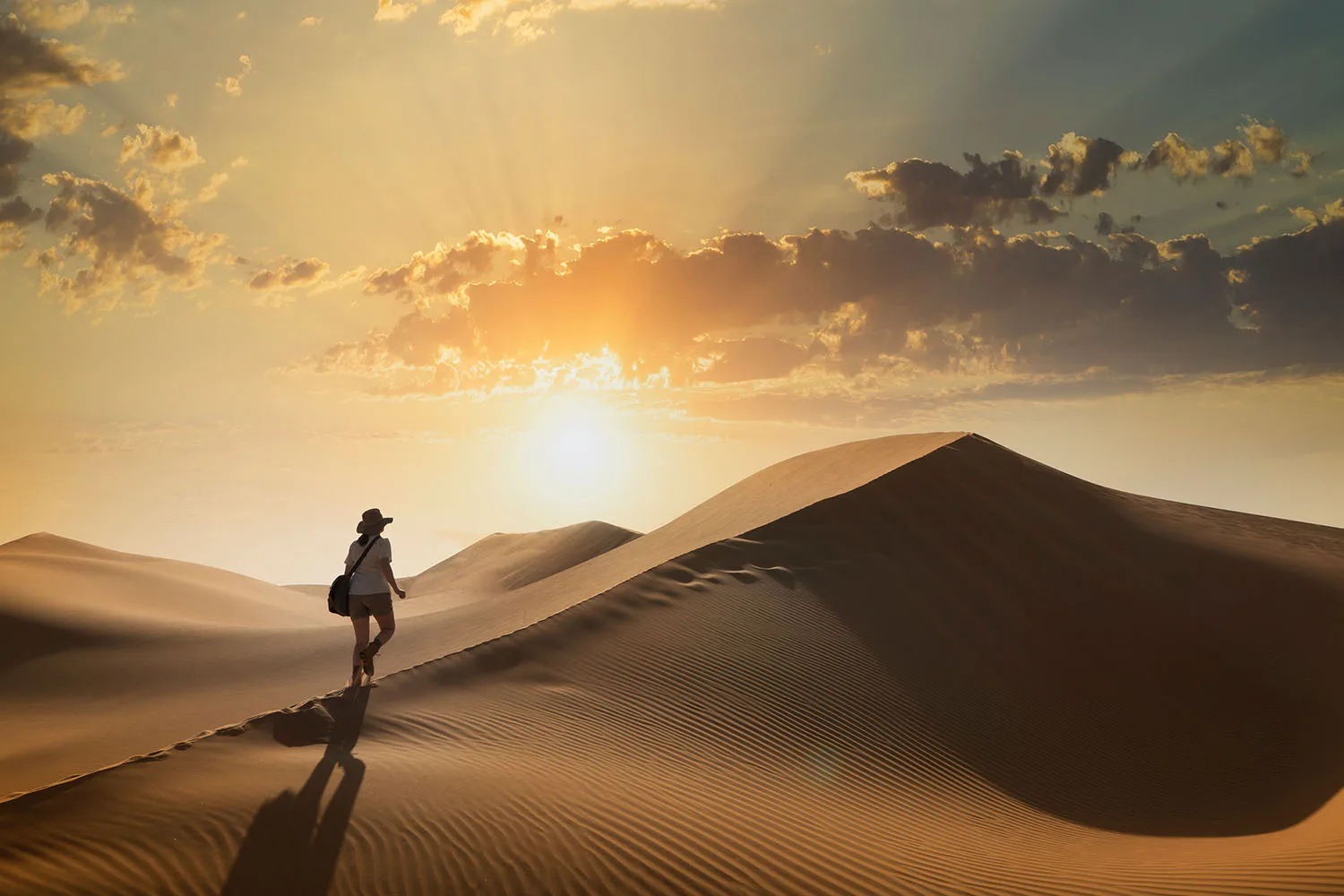woman walking across sand dunes