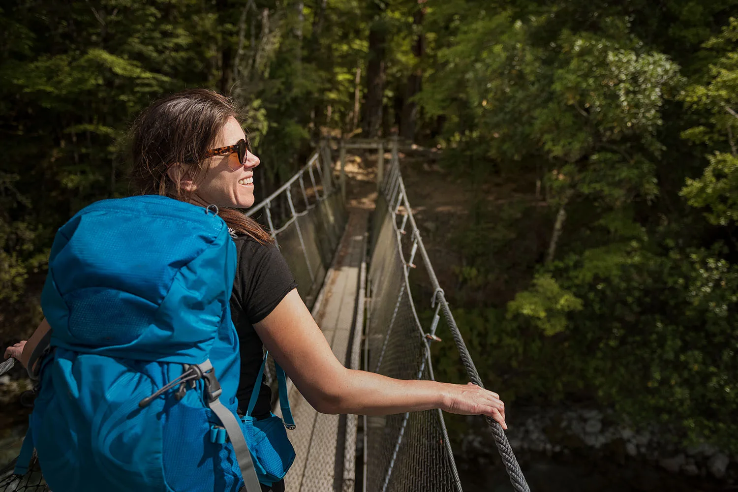 woman walking across bridge in forest