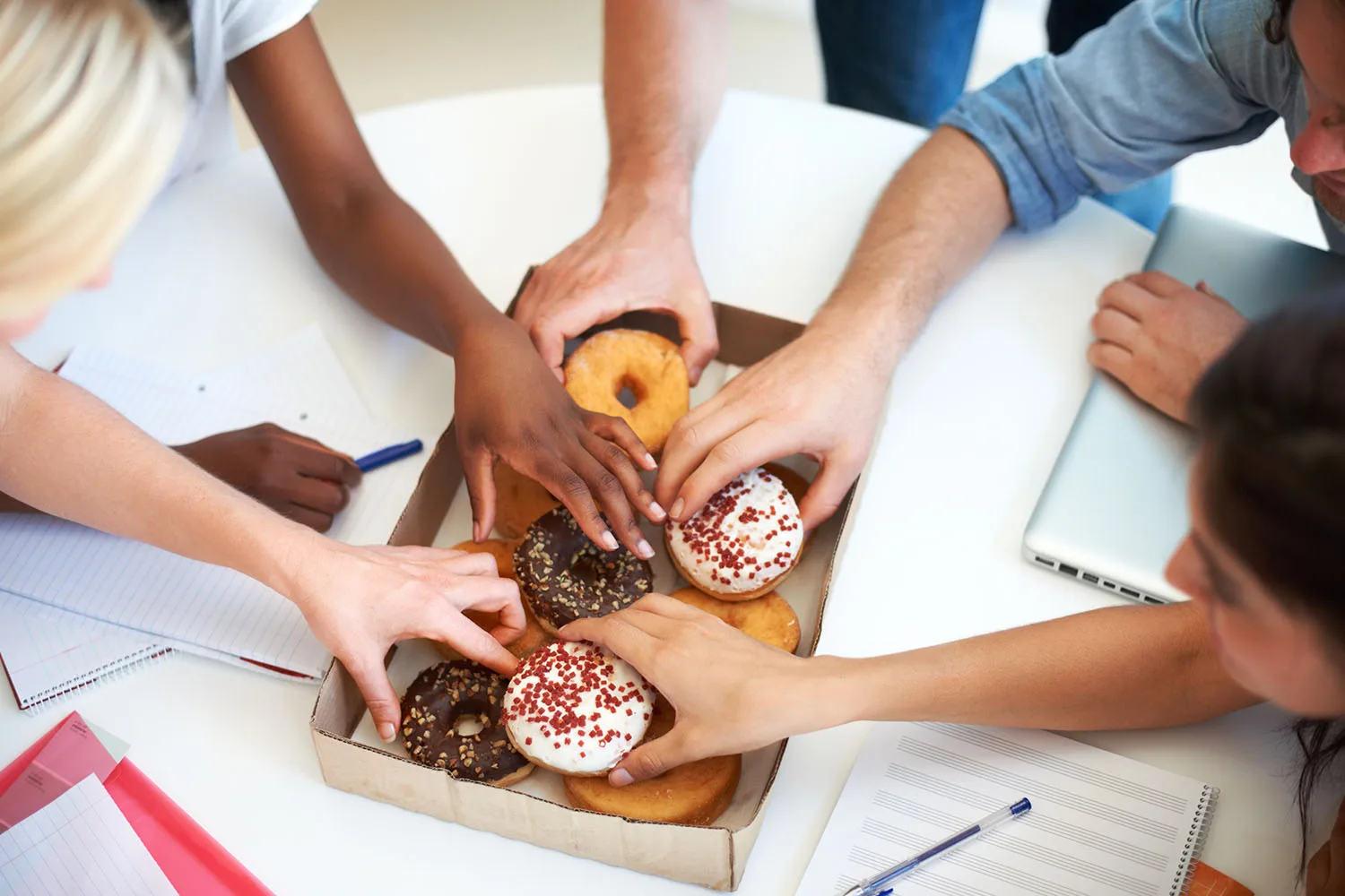 lots of people reaching for a doughnut