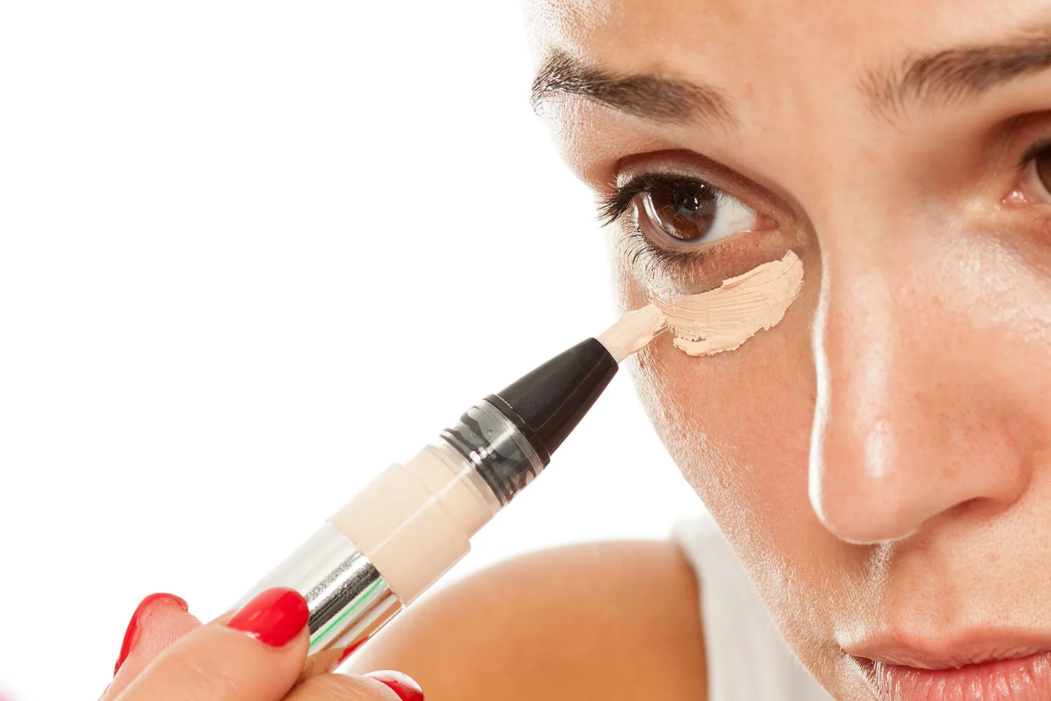 woman applying concealer to under eye area