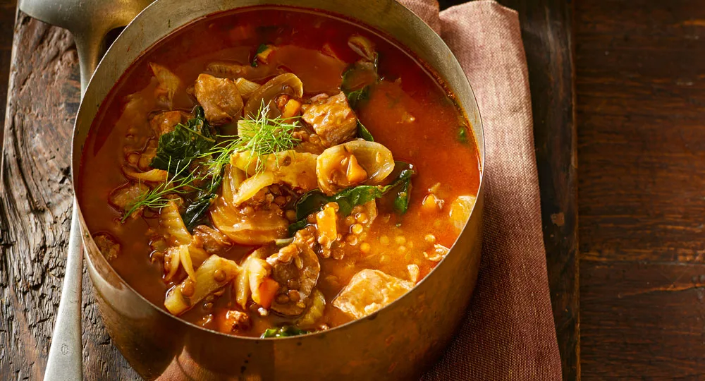 Hearty veal, lentil and vegetable soup with green olive salsa