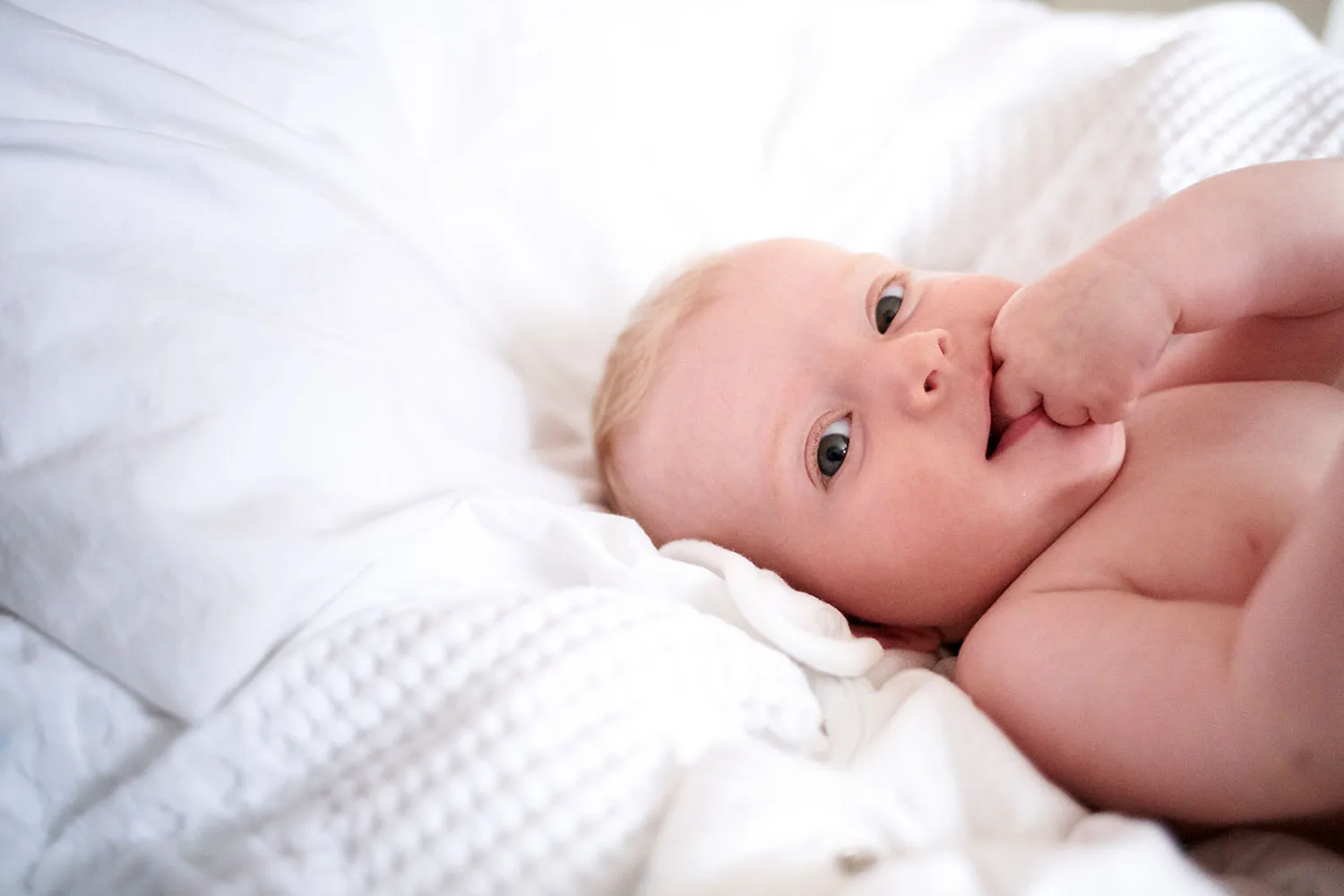 baby lying on white sheets