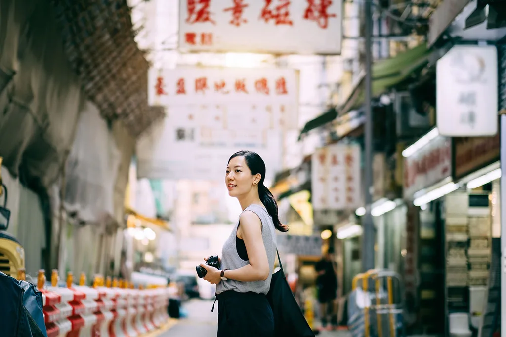 woman walking through street holding camera