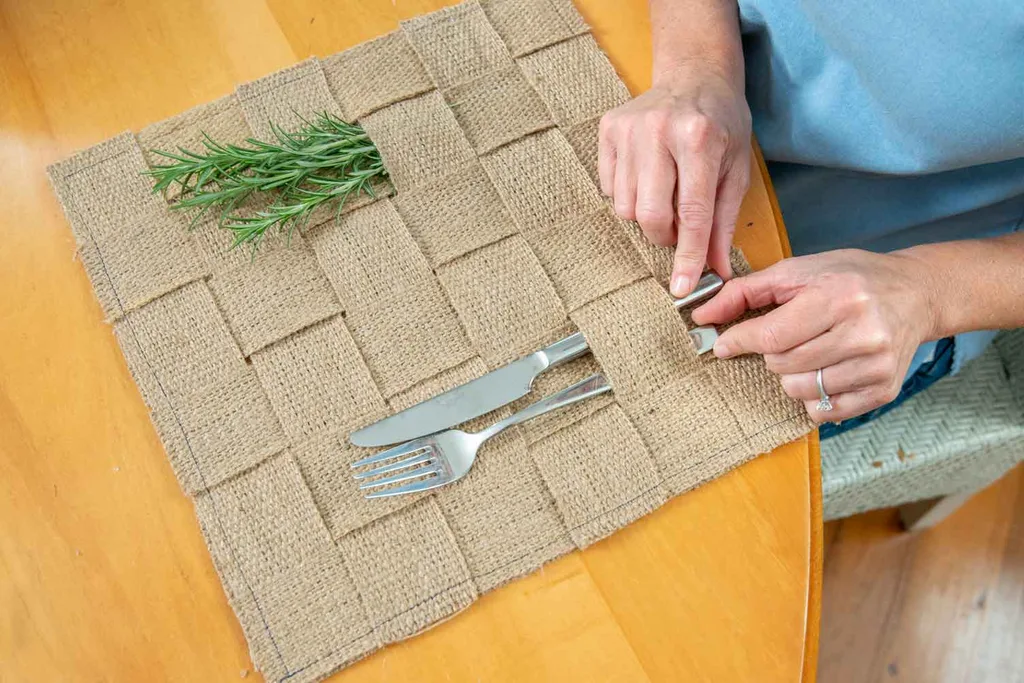 Sprigs of aromatic rosemary and cutlery in woven table linen.