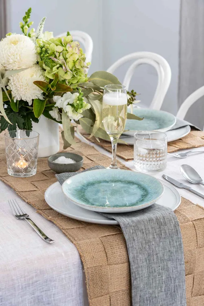 Jute placemats and a runner providing an organic and textured backdrop to a formal table setting.
