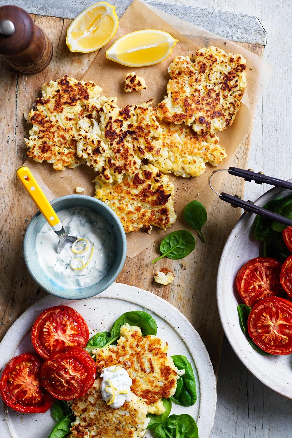 Cauliflower and parmesan fritters with roasted tomatoes on a bowl and yellow spoon