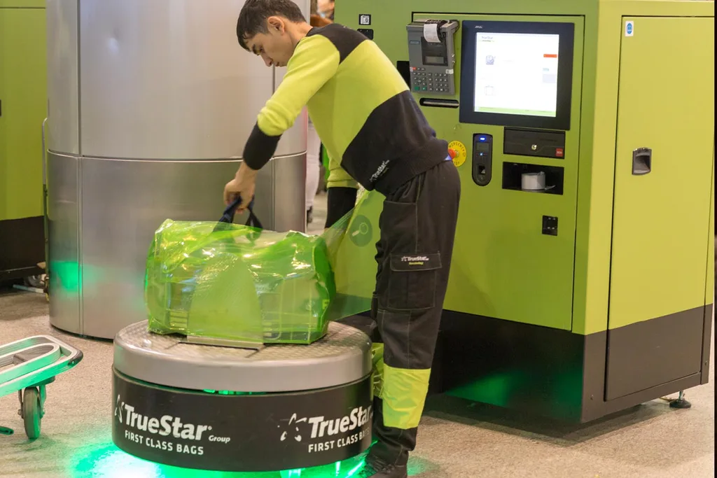 man wrapping suitcase plastic