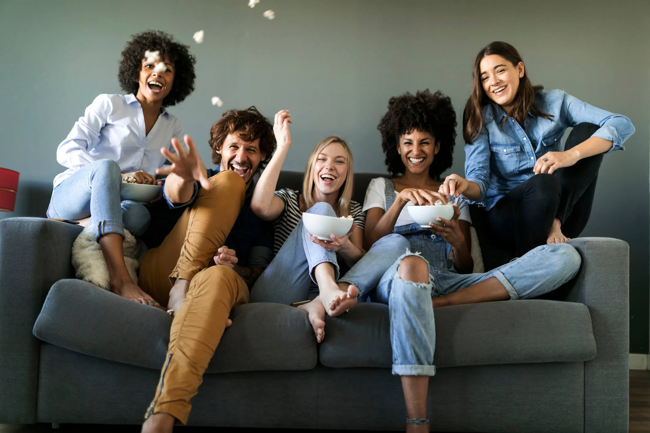 Friends eating popcorn on a couch