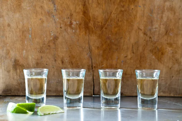 A row of tequila shots against a wooden backdrop