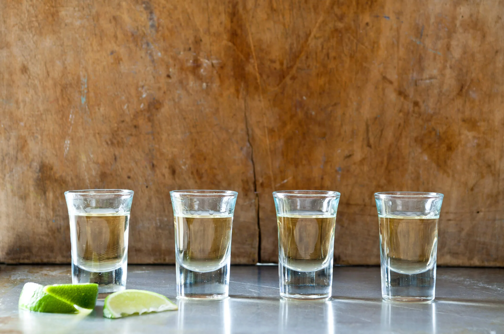 A row of tequila shots against a wooden backdrop