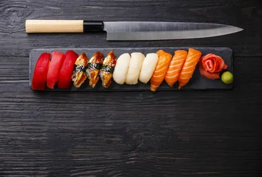 Sashimi on sushi next to a chef's knife