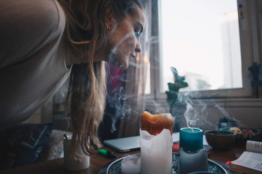 A girl blowing out a scented candle in a window