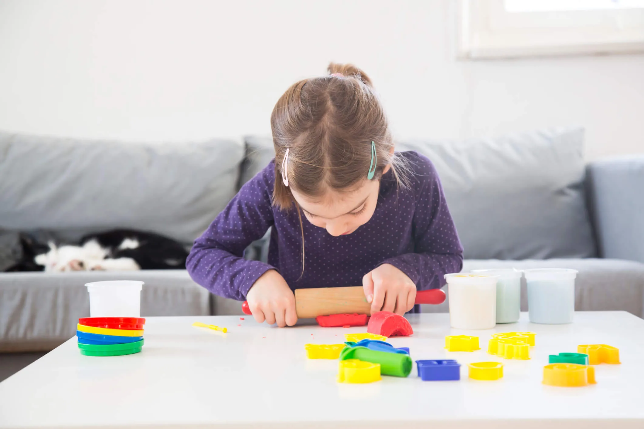 A young girl rolling playdough on a table