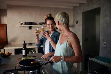 Two friends having a drink while cooking dinner
