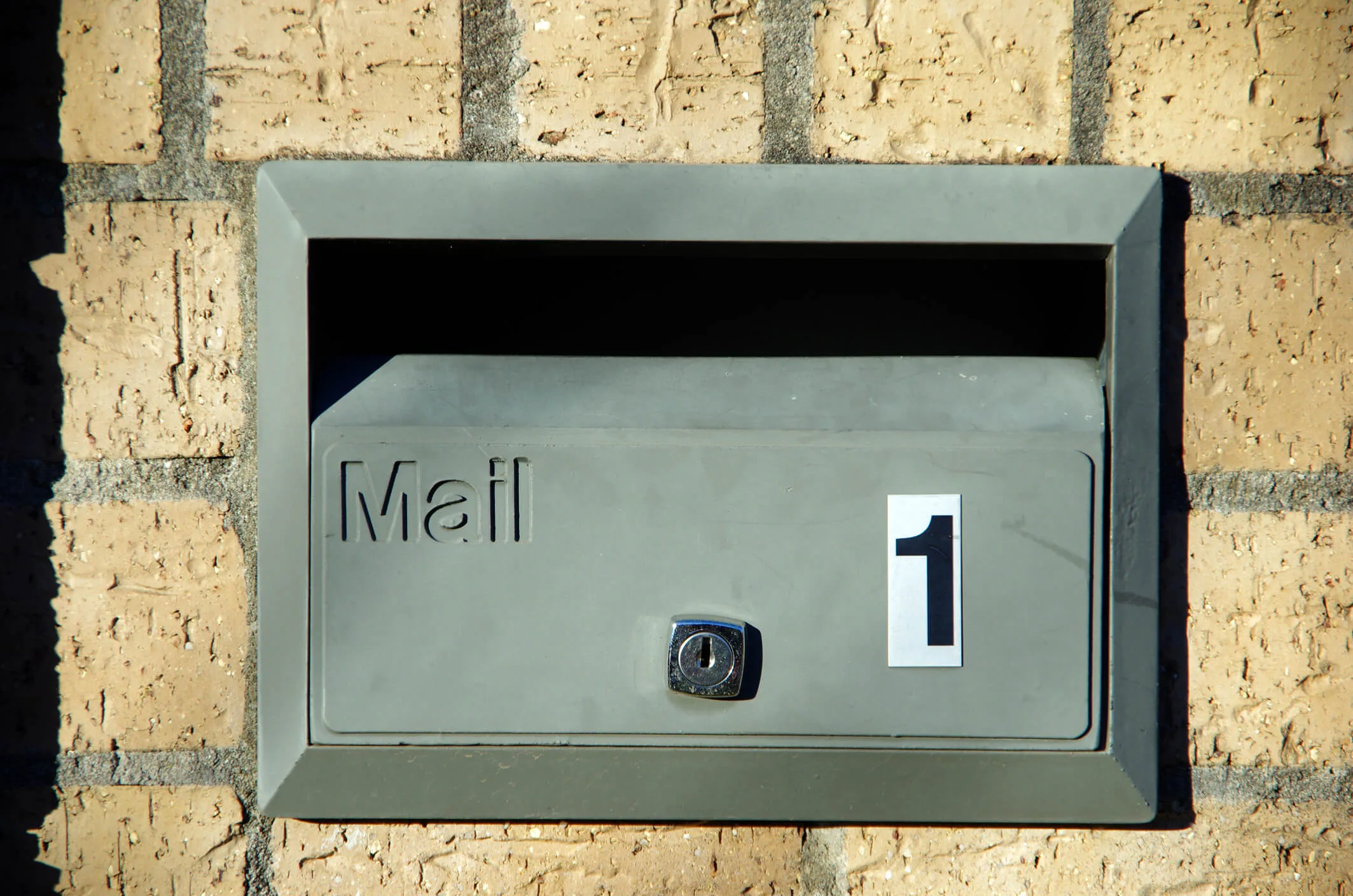 Green mailbox on a cream brick wall