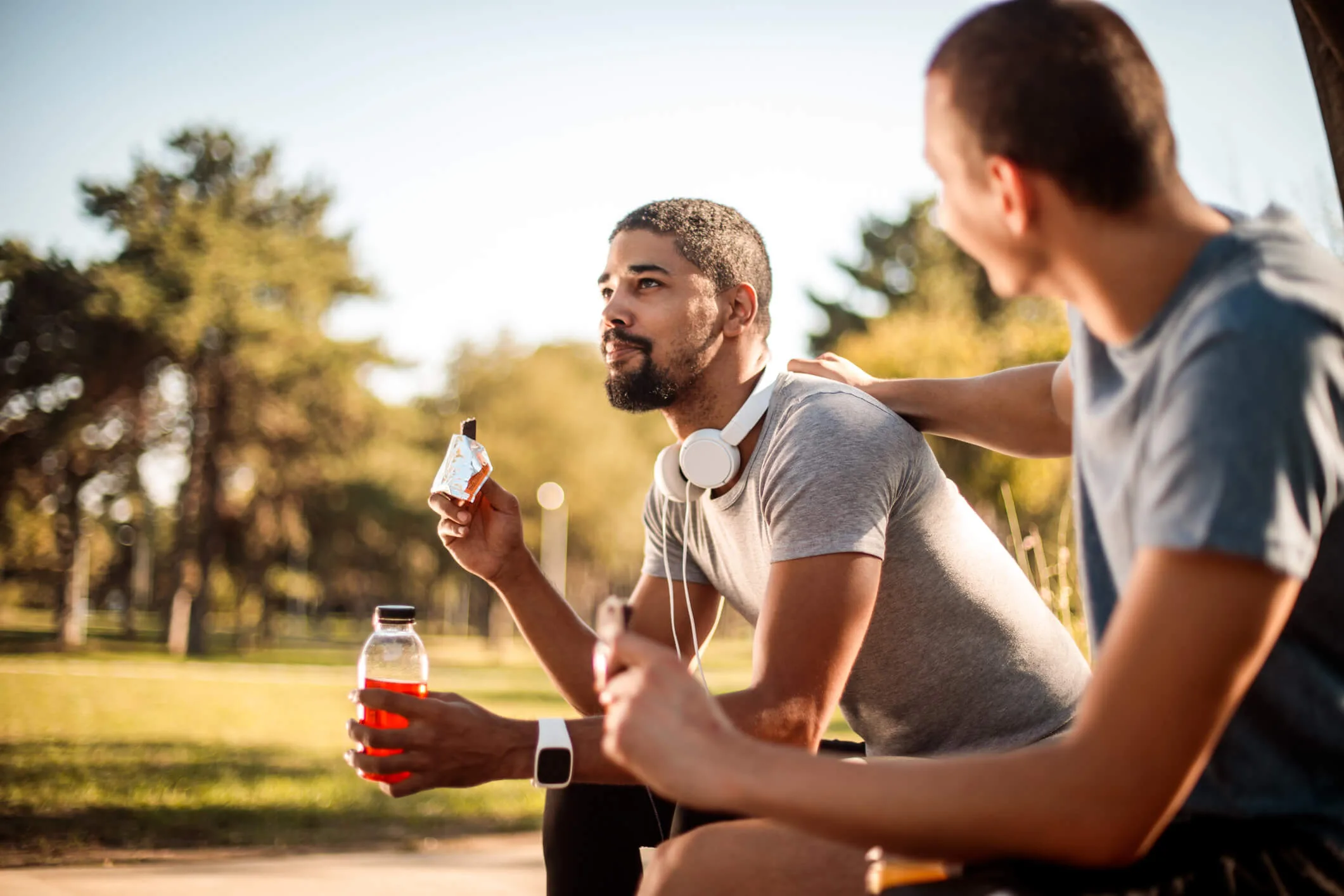 Two runners drinking sports drinks in the park