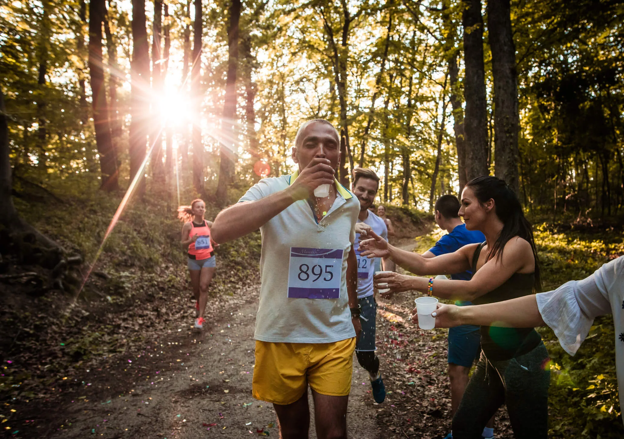 Marathon runners drinking at a water rest-stop in the forest