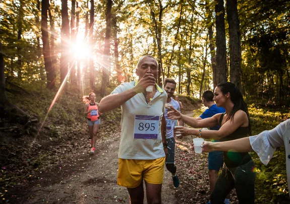 Marathon runners drinking at a water rest-stop in the forest