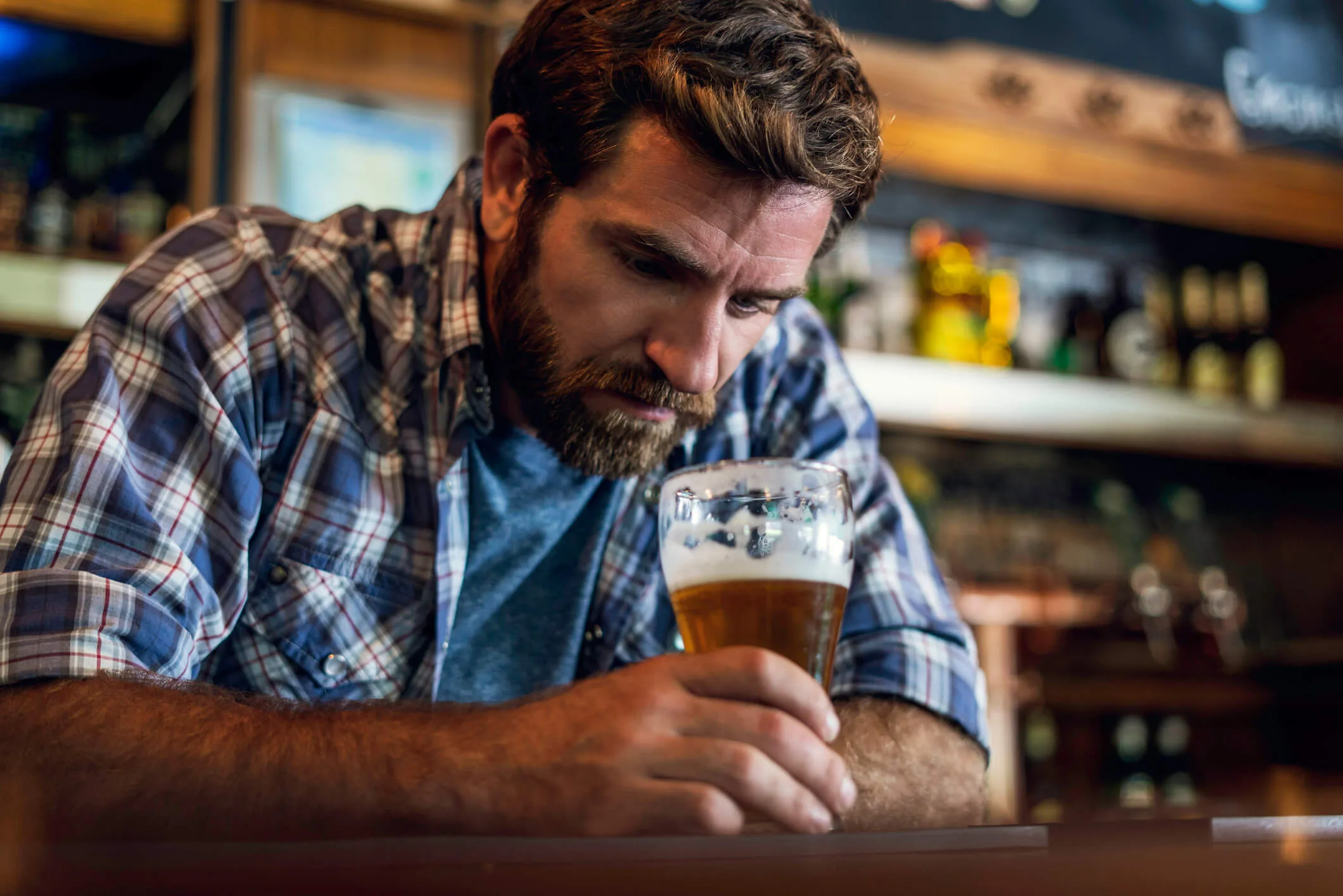 A sad looking man at a bar drinking beer