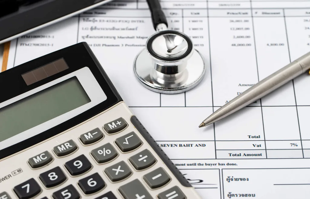 A calculator, stethoscope and pen sitting on an invoice