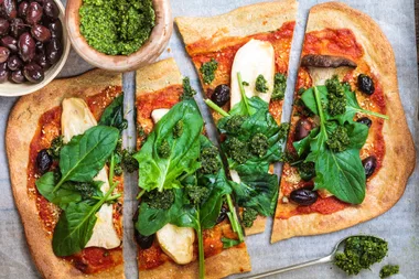 A quinoa pizza base with hummus and spinach