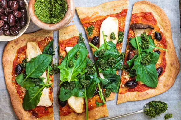 A quinoa pizza base with hummus and spinach