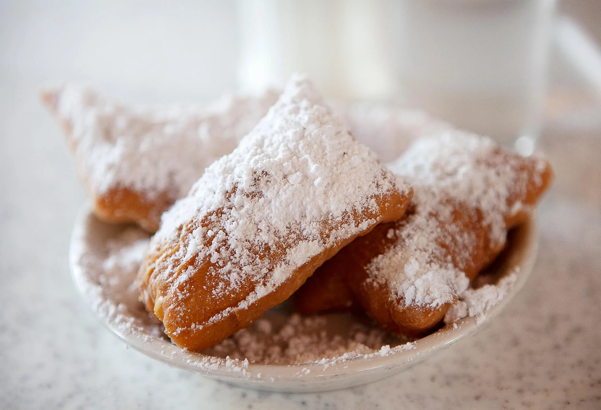 Beignets in a white ceramic bowl with powdered sugar