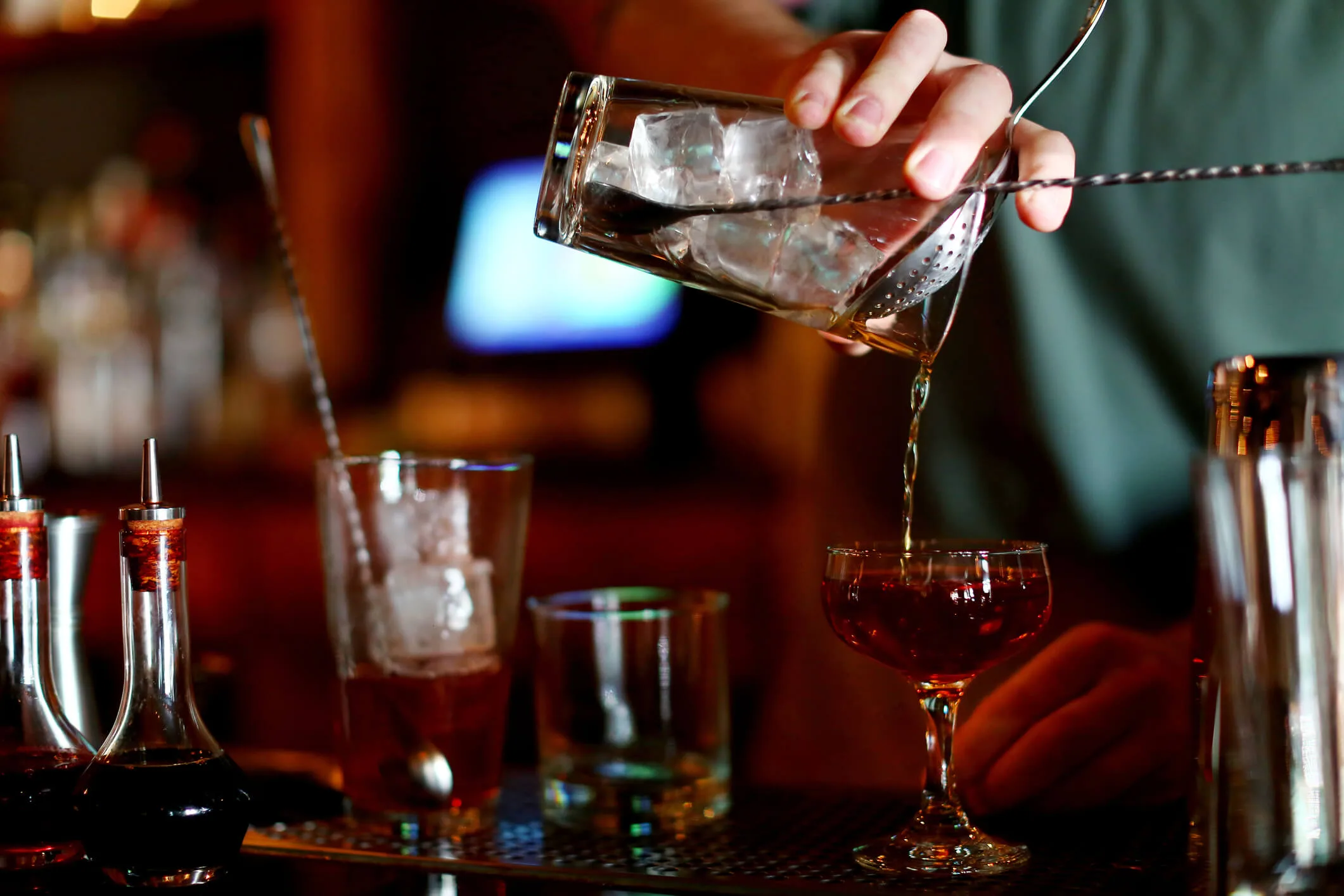 A guy pouring a cocktail into a glass