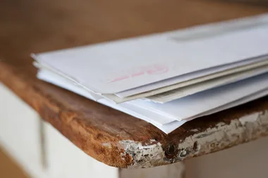 A pile of letters on a wooden table