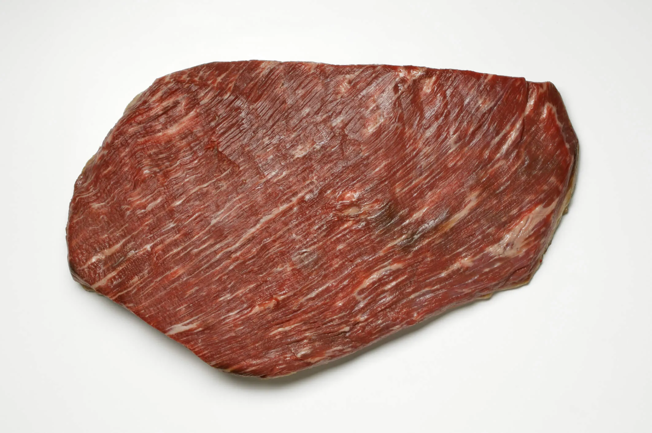 An uncooked beef brisket on a white background